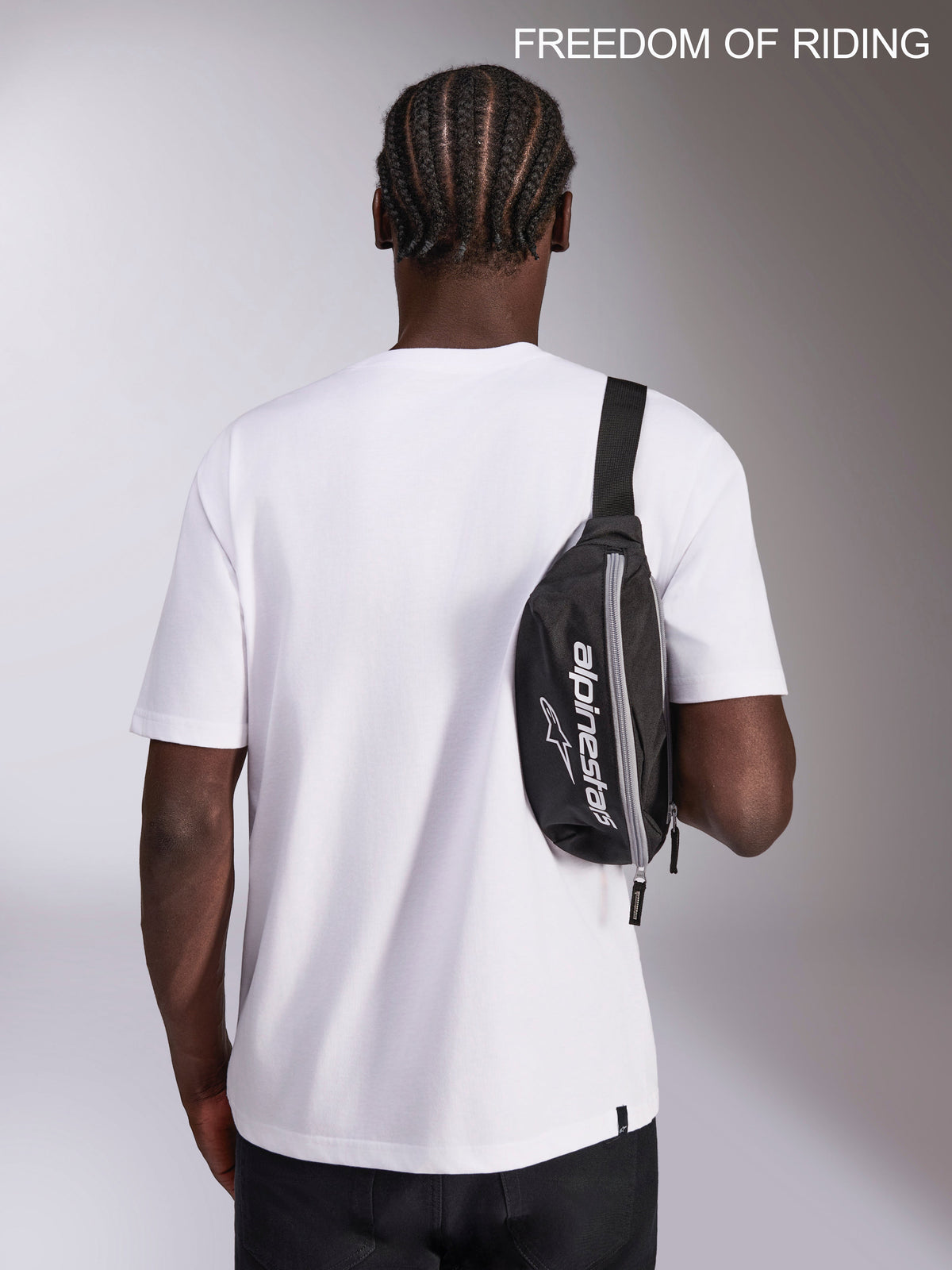 Alpinestars Marsupio Only Linear, borsa sportswear urban, nero e bianco, capacità 2L, 100% poliestere con logo Alpinestars, indossato come borsa a tracolla crossbody da un modello per spostamenti quotidiani e viaggi.
