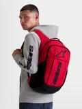 Alpinestars Zaino GFX Boss, zaino sportivo urban da 20L, rosso e nero, indossato da un modello con felpa grigia. Caratterizzato da una struttura in poliestere 600D, scomparto interno per laptop e grafica Astars in silicone in rilievo. Ideale per l'uso quotidiano.