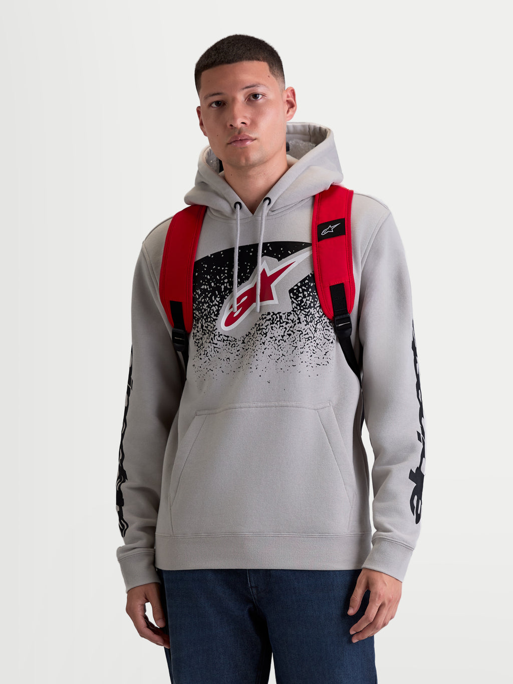 Alpinestars zaino GFX Boss, zaino urban sportswear unisex da 20 litri, rosso e nero, in poliestere 600D resistente, vista frontale su modello con spallacci regolabili in rete traspirante e marchio Astars in silicone.