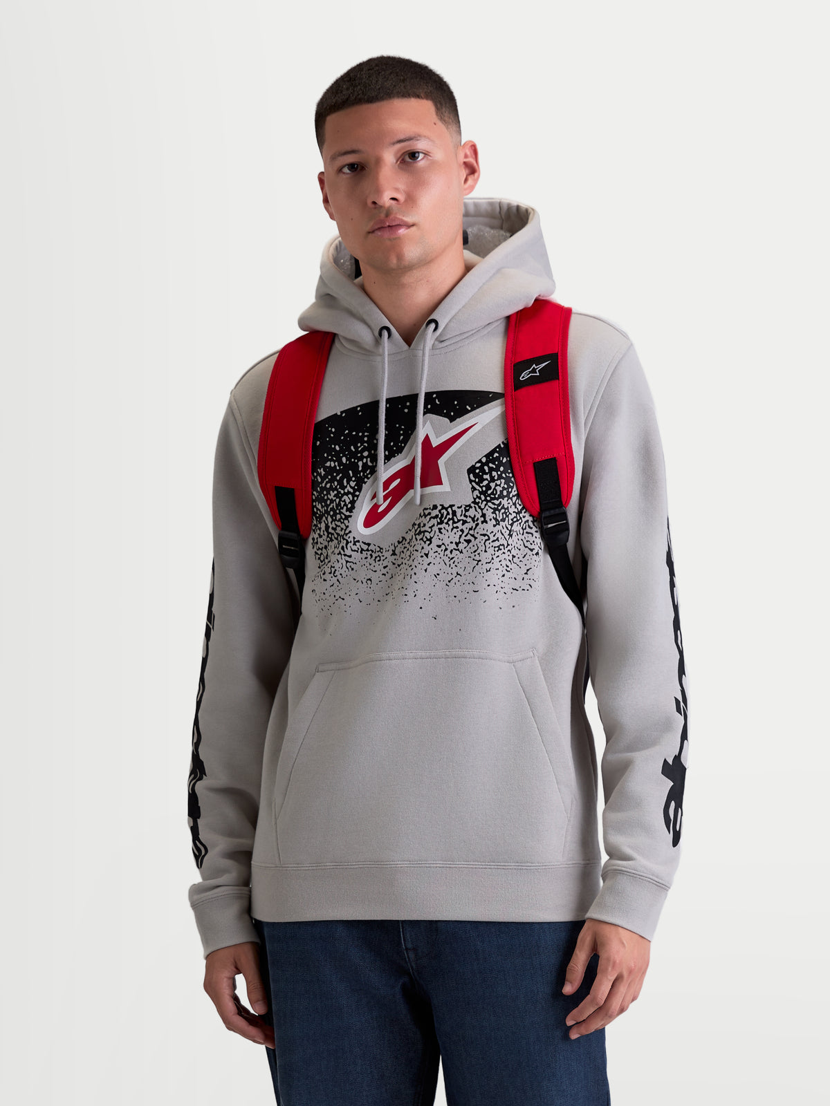 Alpinestars zaino GFX Boss, zaino urban sportswear unisex da 20 litri, rosso e nero, in poliestere 600D resistente, vista frontale su modello con spallacci regolabili in rete traspirante e marchio Astars in silicone.