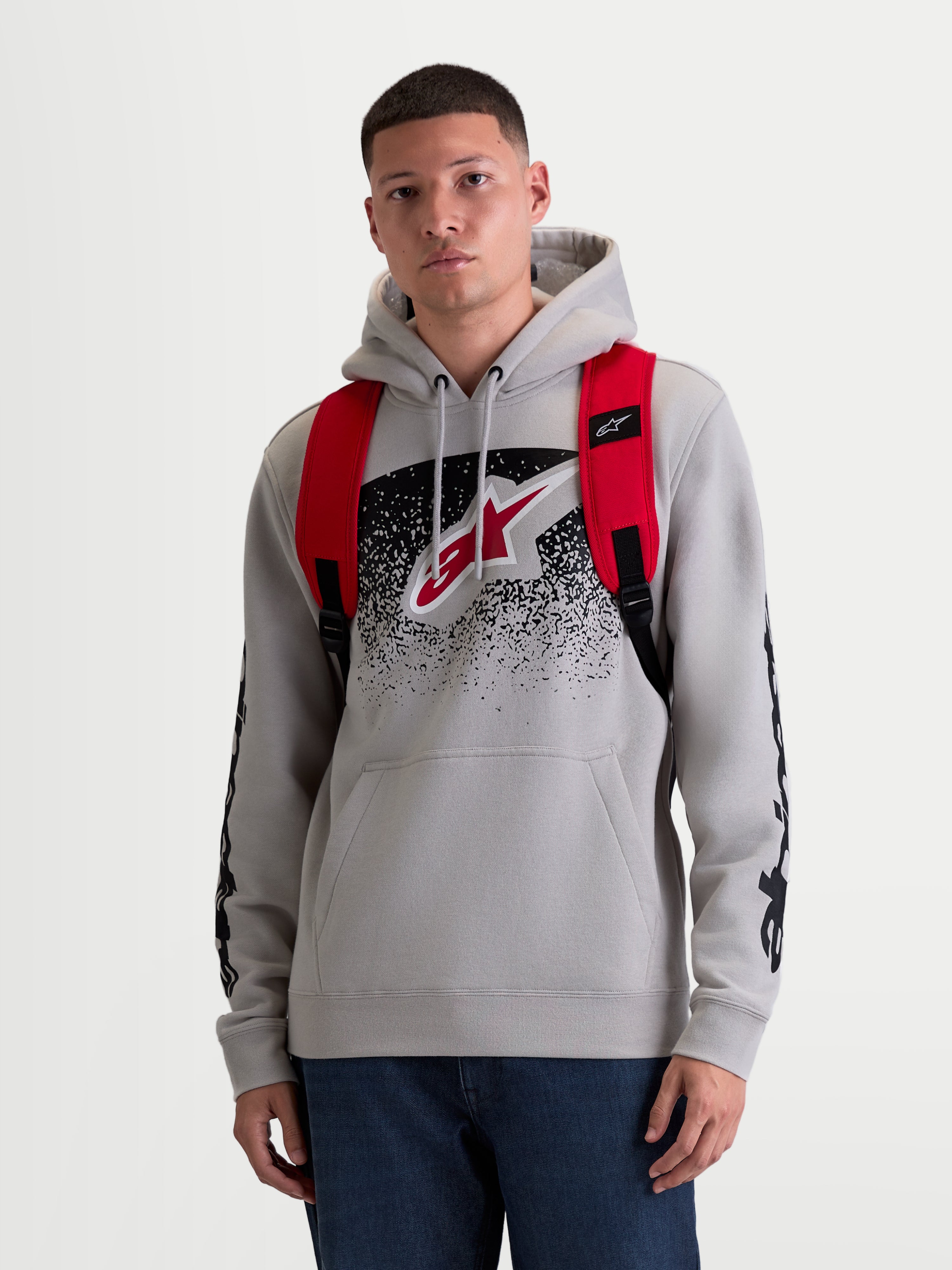 Alpinestars zaino GFX Boss, zaino urban sportswear unisex da 20 litri, rosso e nero, in poliestere 600D resistente, vista frontale su modello con spallacci regolabili in rete traspirante e marchio Astars in silicone.