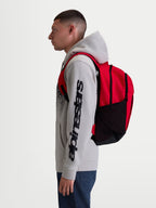 Alpinestars zaino GFX Boss, zaino sportivo da 20L per uomo e donna, rosso e nero, in poliestere resistente con tasche laterali in rete e spallacci imbottiti, vista laterale su modello per uso quotidiano e urbano