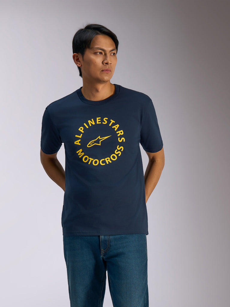 Alpinestars MX CSF Tee, t-shirt a maniche corte, blu navy, grafica circolare gialla Alpinestars Motocross con logo a stella centrale, indossata da un uomo con jeans blu, streetwear casual motorsport