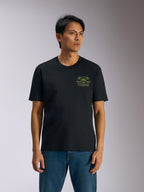 Alpinestars Order CSF Tee, maglietta a maniche corte, nera, grafica verde con casco e palme sul petto, indossata con jeans blu, abbigliamento casual motorsport streetwear