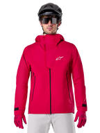 Alpinestars A-Dura Elite Waterproof Jacket, giacca antipioggia per mountain bike, rosso fluo, collo alto con logo Alpinestars bianco, dettagli con zip nera, indossata con guanti coordinati e casco da ciclismo nero, abbigliamento tecnico impermeabile da ciclismo