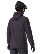 Alpinestars Giacca Termica A-Dura, nero, vista posteriore, indossata con casco da mountain bike e guanti neri, presenta un piccolo logo Astars bianco sulla parte bassa della schiena, giacca da ciclismo isolante e leggera