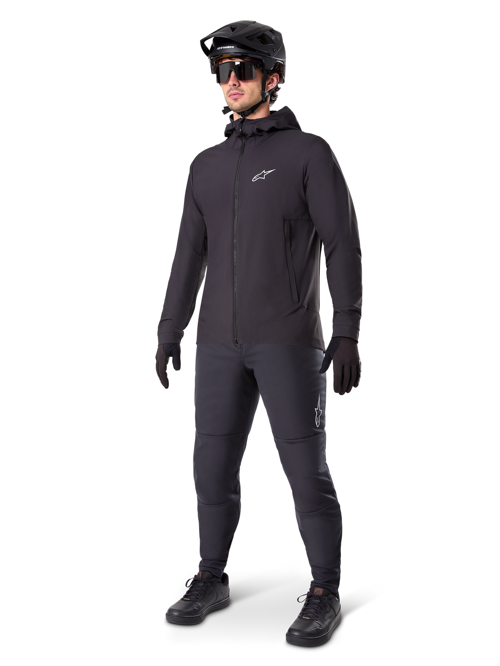 Giacca termica Alpinestars A-Dura in nero, indossata da un ciclista con equipaggiamento completo da mountain bike tra cui casco nero, occhiali da sole e pantaloni da ciclismo, giacca con cappuccio leggera e isolata per prestazioni ciclistiche in climi freddi