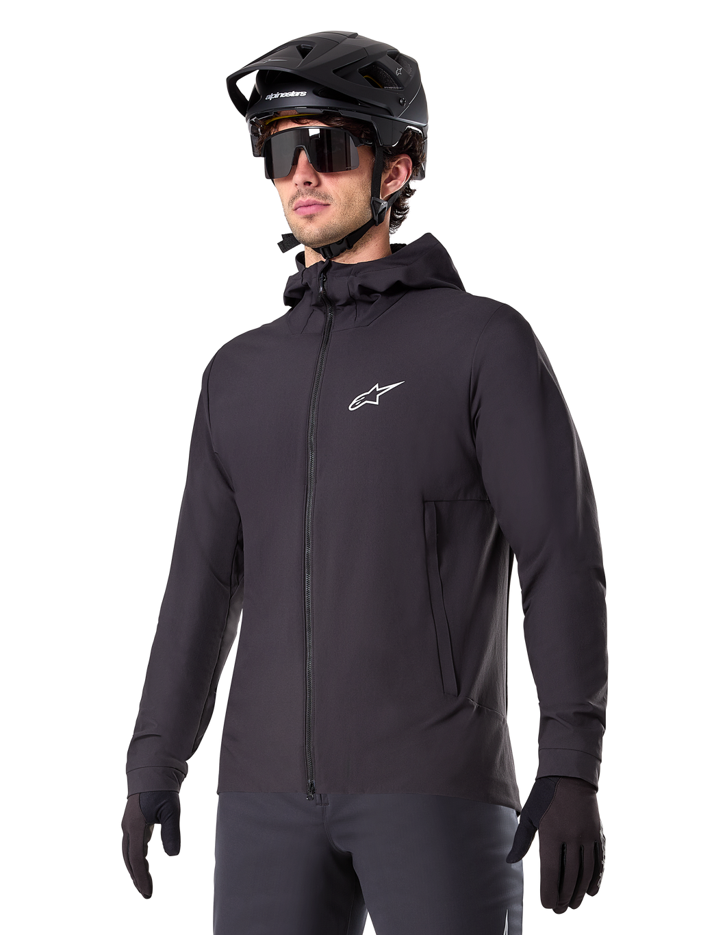 Alpinestars A-Dura Thermal Jacket, giacca da ciclismo nera, design con cappuccio e zip frontale, logo a stella bianco sul petto, indossata con casco da mountain bike e guanti neri, abbigliamento sportivo per il trail riding in climi freddi