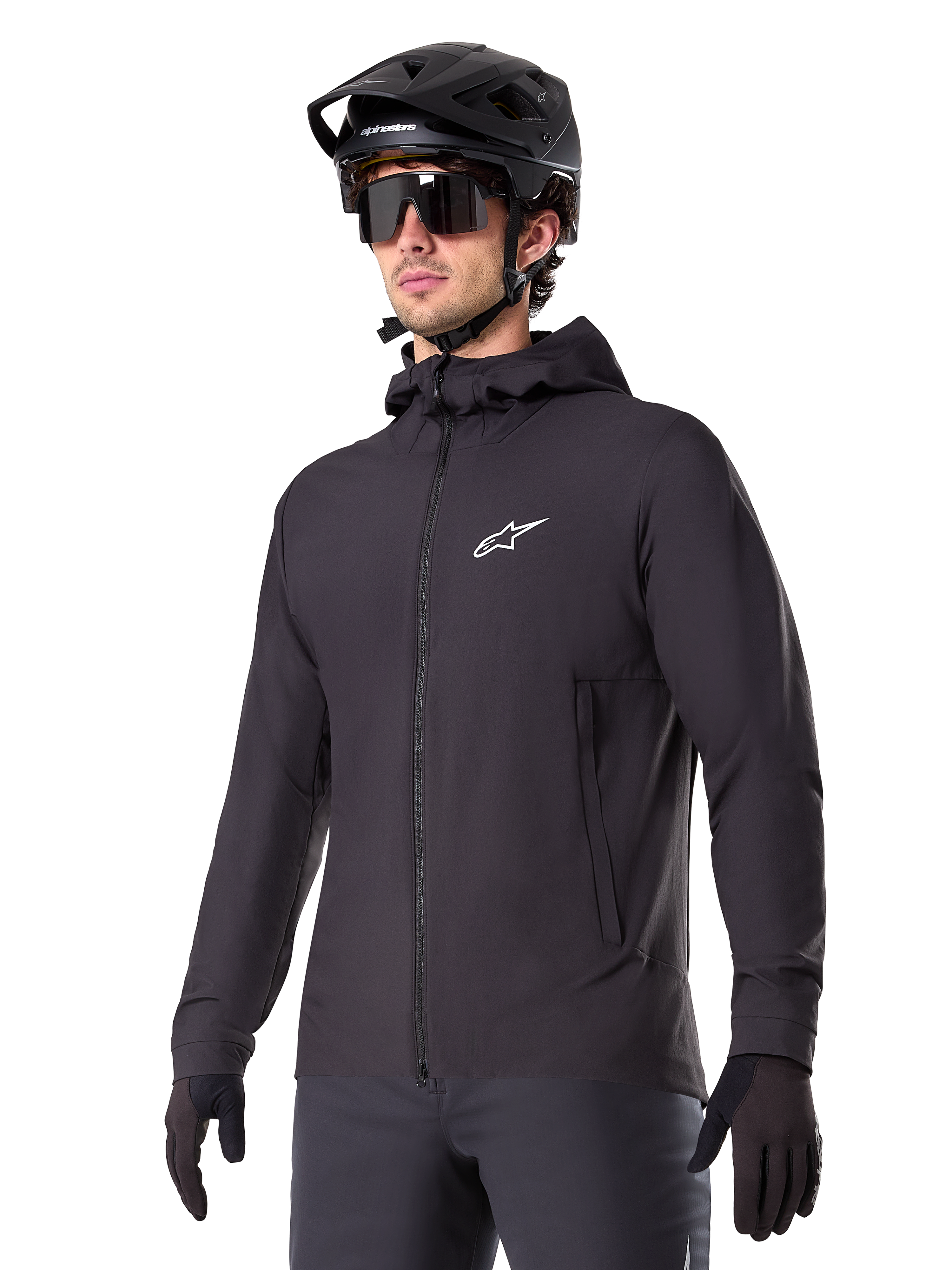 Alpinestars A-Dura Thermal Jacket, giacca da ciclismo nera, design con cappuccio e zip frontale, logo a stella bianco sul petto, indossata con casco da mountain bike e guanti neri, abbigliamento sportivo per il trail riding in climi freddi
