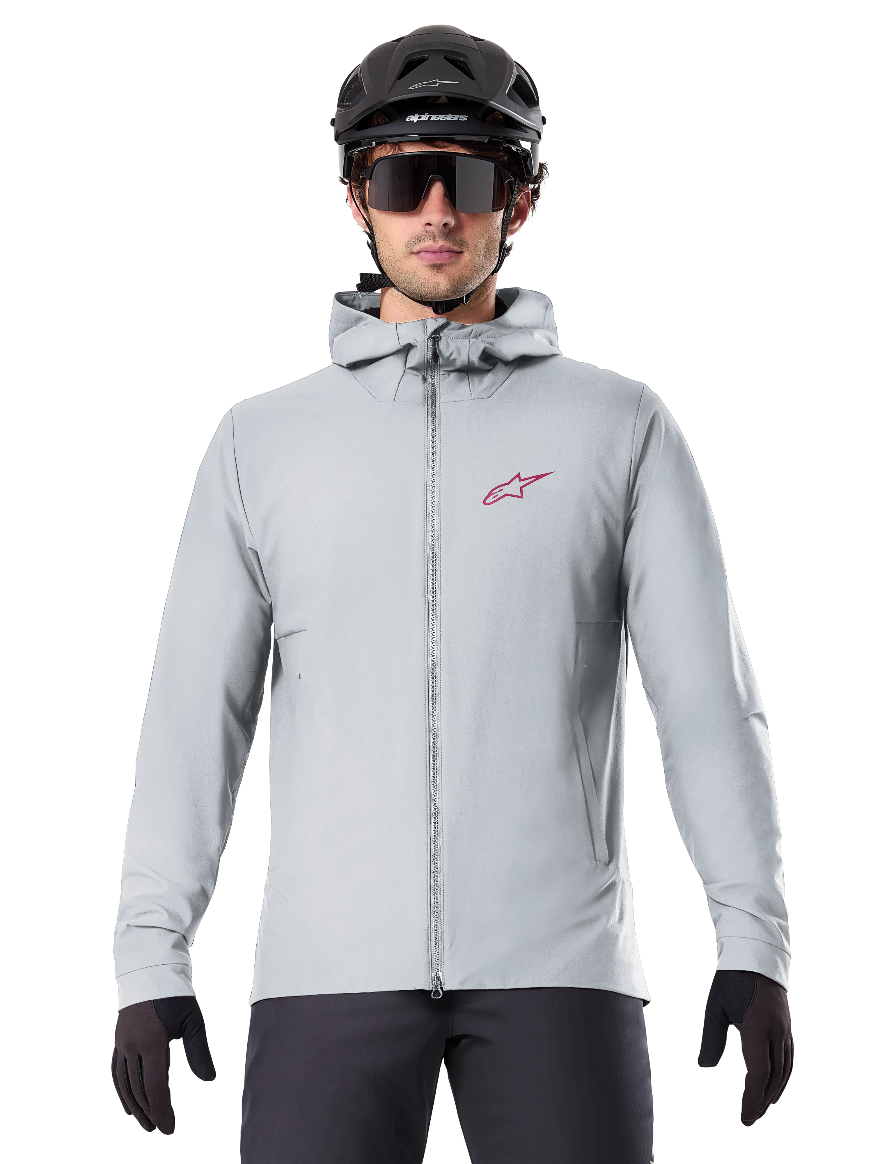 Alpinestars A-Dura Thermal Jacket in Titanium, giacca da ciclismo grigio chiaro con cappuccio e logo a stella rosso sul petto, indossata da un rider con casco da MTB nero, occhiali da sole e guanti, abbigliamento isolante per mountain bike