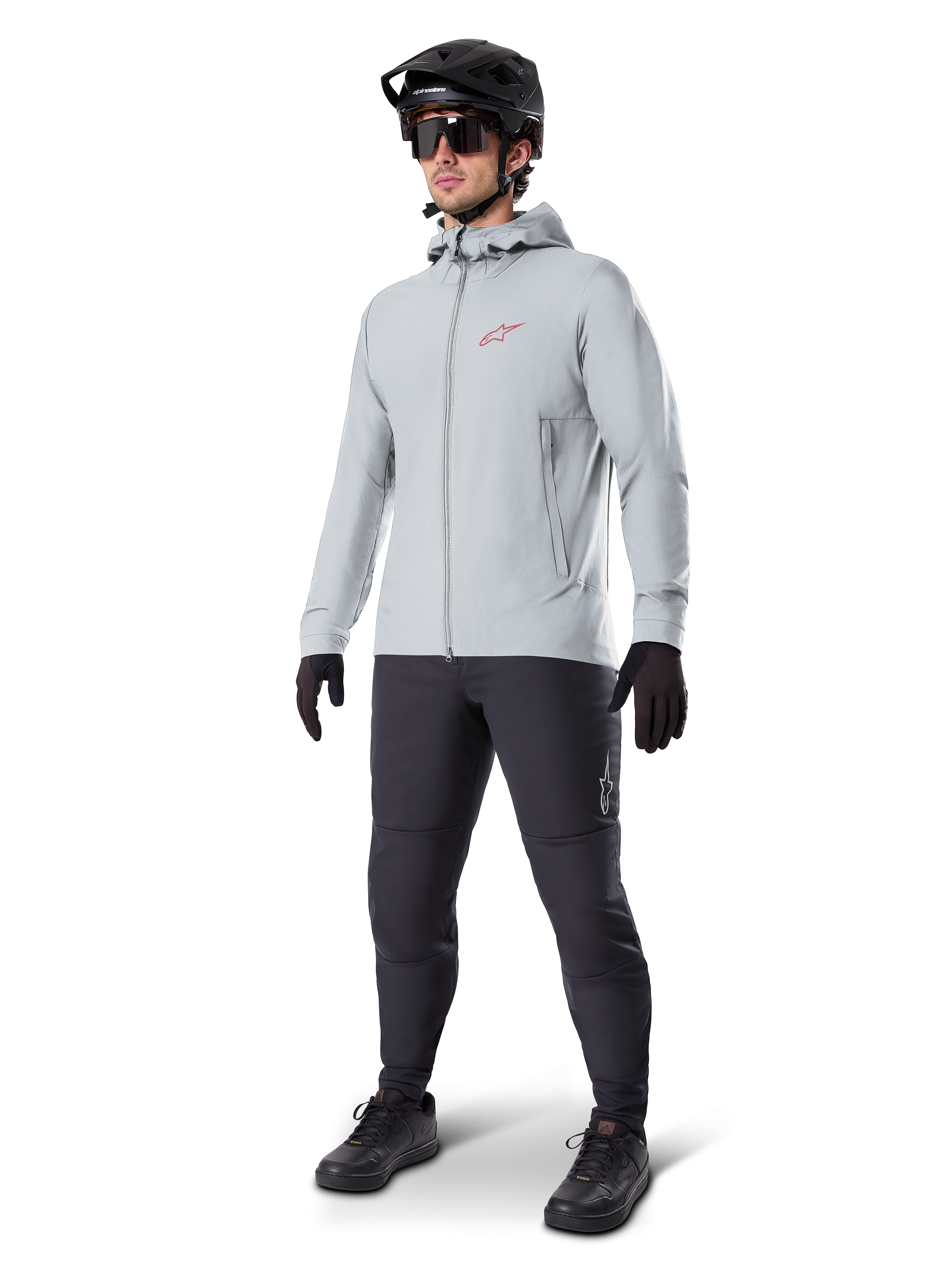 Giacca termica Alpinestars A-Dura in Titanium, giacca da ciclismo grigio chiaro con cappuccio e logo Alpinestars rosso sul petto, indossata da un uomo con casco da MTB nero, occhiali da sole, pantaloni grigio scuro e guanti neri, attrezzatura professionale da mountain bike