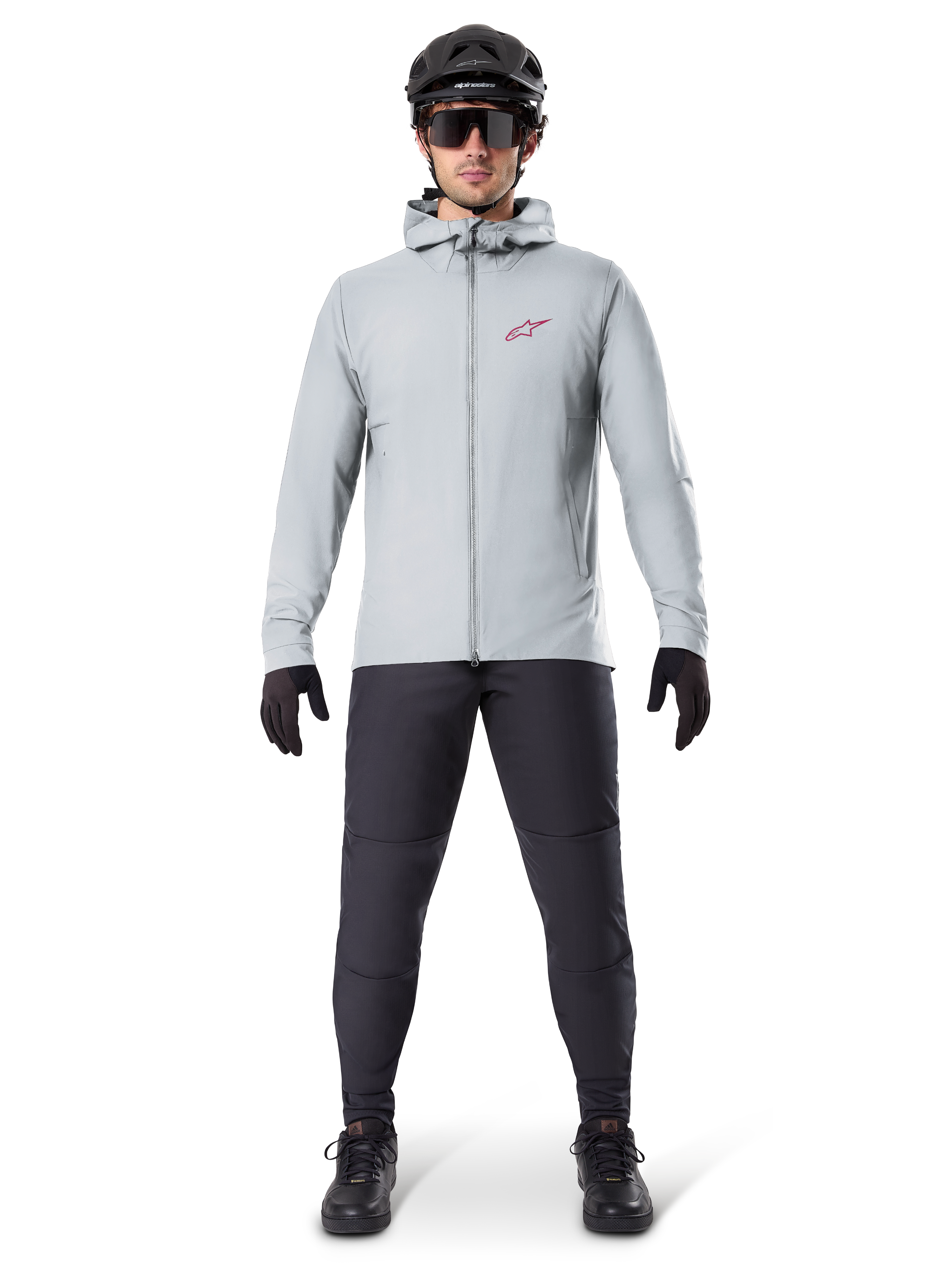 Giacca Termica Alpinestars A-Dura, grigio titanio, giacca da ciclismo indossata con pantaloni da mountain bike neri, guanti e casco, caratterizzata da un piccolo logo a stella rosso sul petto e cerniera frontale completa, abbigliamento isolante leggero per la guida fuoristrada
