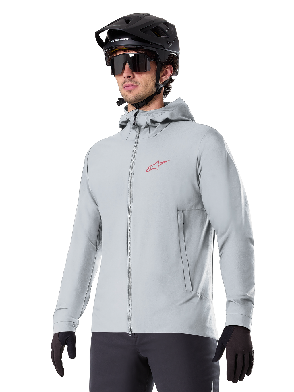 Alpinestars A-Dura Thermal Jacket, giacca termica da ciclismo grigio chiaro, design con cappuccio e piccolo logo rosso, indossata con casco e guanti neri, abbigliamento tecnico da mountain bike per il freddo