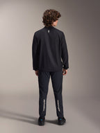 Giacca frangivento Alpinestars A-Aria, nero, vista posteriore, giacca da ciclismo leggera e resistente al vento con un piccolo logo bianco sulla parte superiore della schiena, indossata con pantaloni neri coordinati con marchio Alpinestars verticale sui polpacci, abbigliamento tecnico da mountain bike