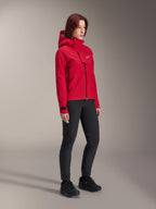 Giacca impermeabile Alpinestars Stella A-Dura Elite da donna, Rosso Fluo, giacca antipioggia con cappuccio per mountain bike con logo Astars bianco sulla patta pettorale, indossata con pantaloni neri e scarpe da mountain bike nere, abbigliamento tecnico ad alte prestazioni per trail riding