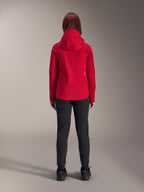 Vista posteriore di una donna che indossa la giacca impermeabile Alpinestars Stella A-Dura Elite in Red Fluo, abbinata a pantaloni e scarpe neri, dotata di un cappuccio protettivo e orlo posteriore allungato per la mountain bike.