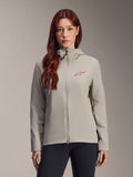 Alpinestars giacca termica Stella A-Dura da donna, grigio titanio, design con cappuccio e zip con logo a stella rosso sul petto, abbinata a pantaloni neri, ritratto lifestyle in studio