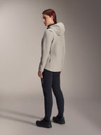 Giacca termica Alpinestars Stella A-Dura in grigio titanio, vista posteriore a tre quarti di una donna che indossa la giacca da ciclismo con cappuccio e pantaloni da MTB neri, scatto in studio con dettaglio della tasca