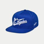 Cappello Alpinestars Los Angeles, cappellino snapback con visiera piatta, blu con ricamo 3D "Los Angeles" bianco in carattere sportivo, logo Ageless laterale, corona strutturata, copricapo casual ispirato al motorsport