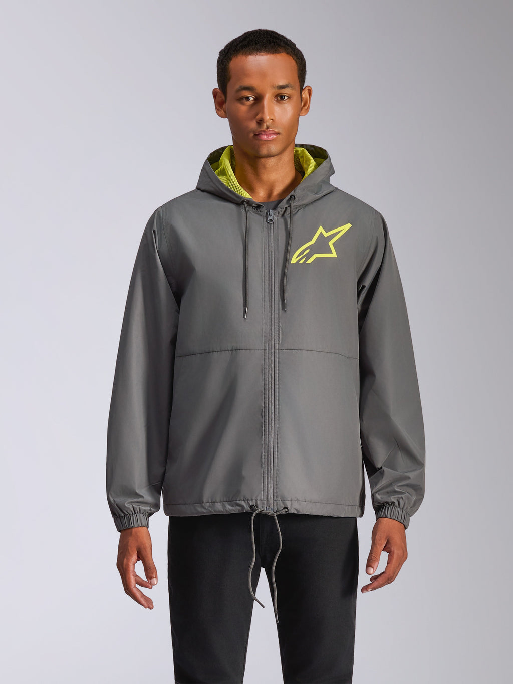 Alpinestars Speeder Chromium Windbreak Jacket, giacca a vento con cappuccio grigio antracite con logo stella giallo fluo, interno cappuccio verde lime, polsini elastici, coulisse regolabili, chiusura frontale con zip, stile motorsport casual