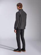 Alpinestars Overhaul Racer Jacket, nera, vista posteriore a tre quarti, indossata da un modello con jeans neri e sneakers nere, giacca guscio antipioggia leggera e resistente all'acqua per uno stile di vita motorsport casual