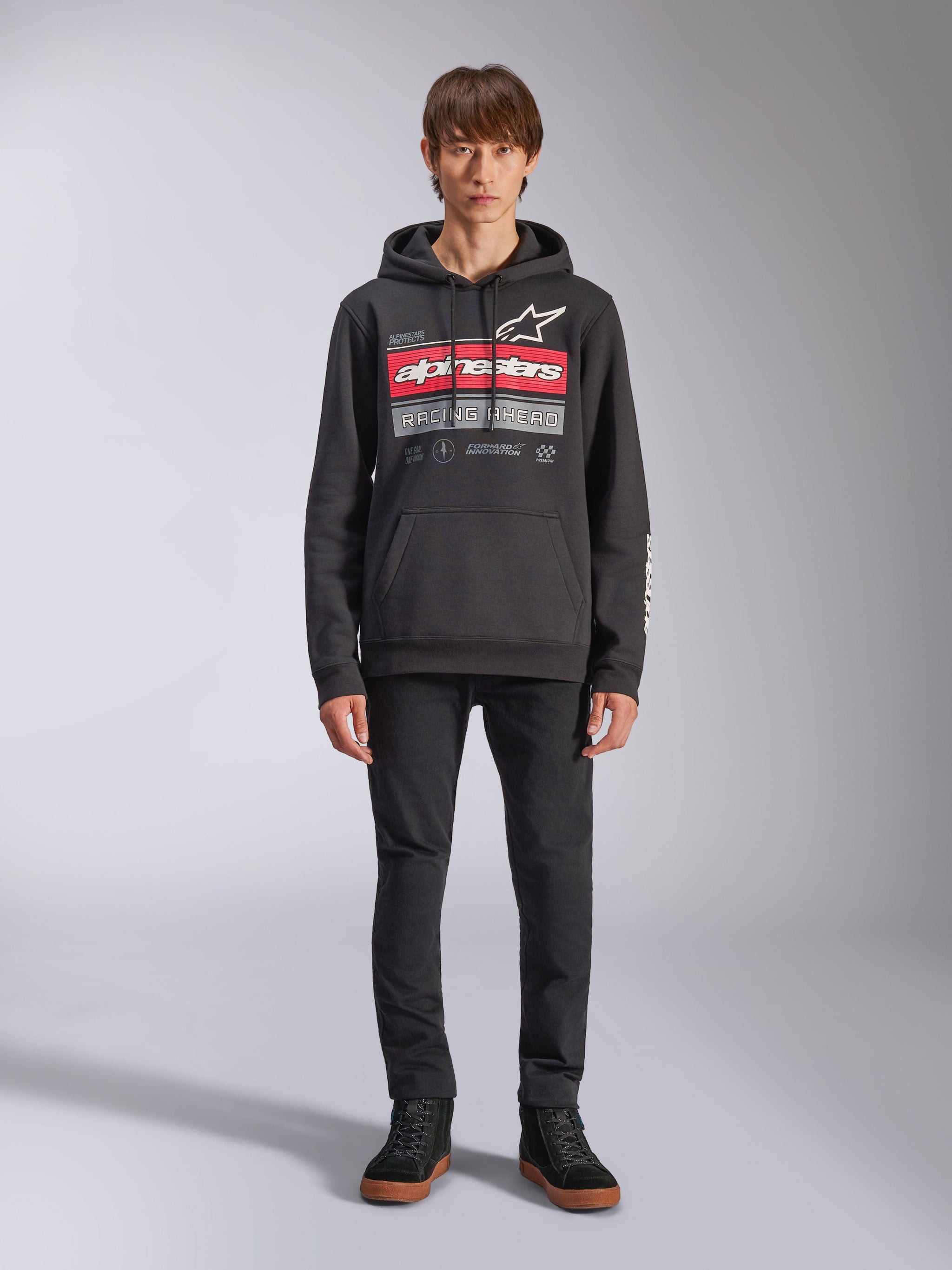 Alpinestars Harken Hoodie, felpa con cappuccio nera, grafica audace sul petto con strisce rosse e scritta 'Racing Ahead', logo Astars bianco, tasca a marsupio, cappuccio con cordino, streetwear casual ispirato al motorsport