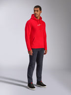 Alpinestars Frontal Hoodie, rossa, modello che indossa una felpa in pile con cappuccio e logo A-star bianco sul petto, tasca a marsupio, cappuccio con cordoncino, abbinata a jeans in denim scuro, streetwear casual ispirato al motorsport