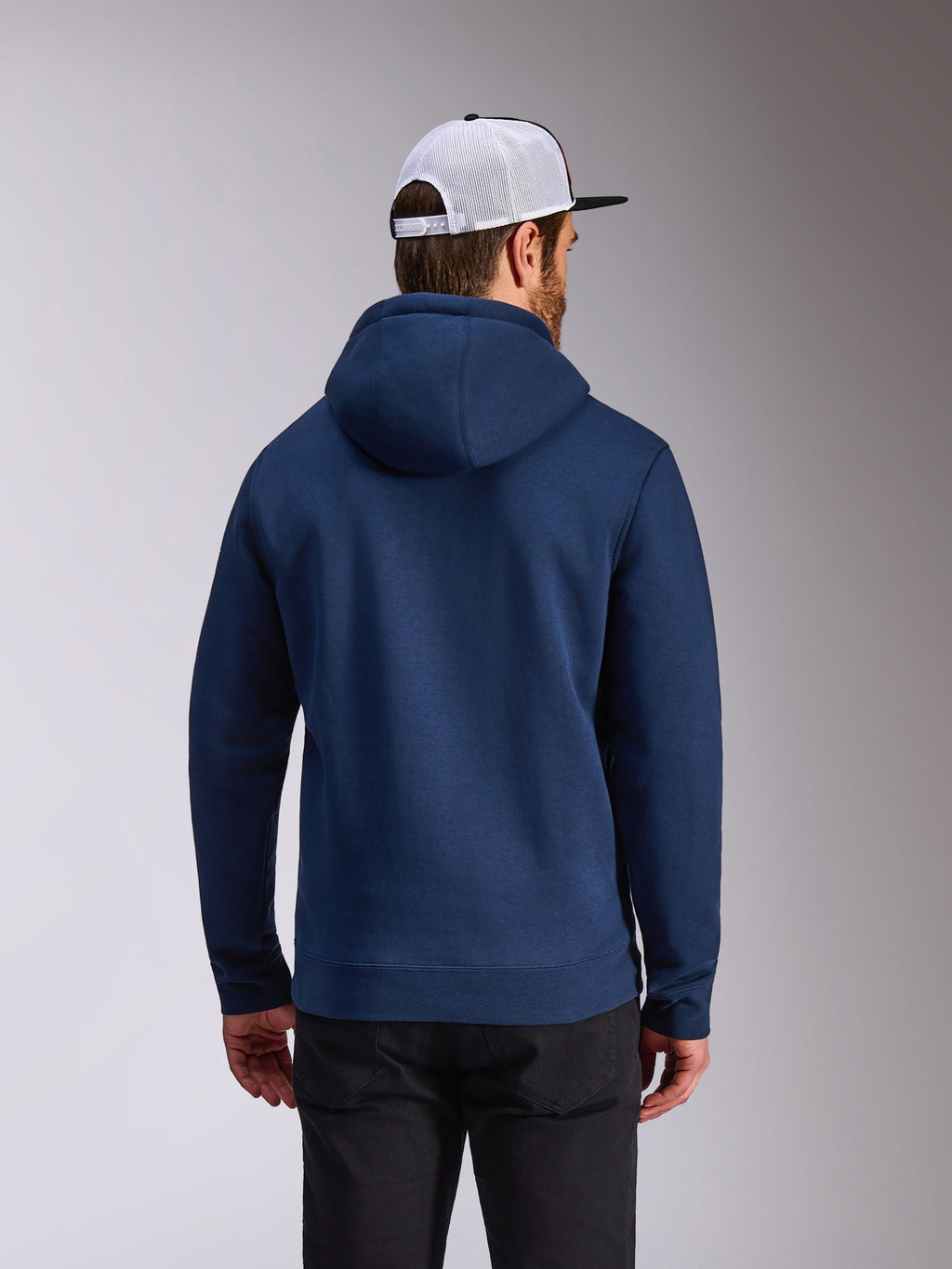 Alpinestars Frontal Hoodie, felpa con cappuccio in pile blu navy, vista posteriore di abbigliamento casual streetwear, indossata con pantaloni neri e cappellino in mesh bianco e nero, design moderno ispirato al motorsport