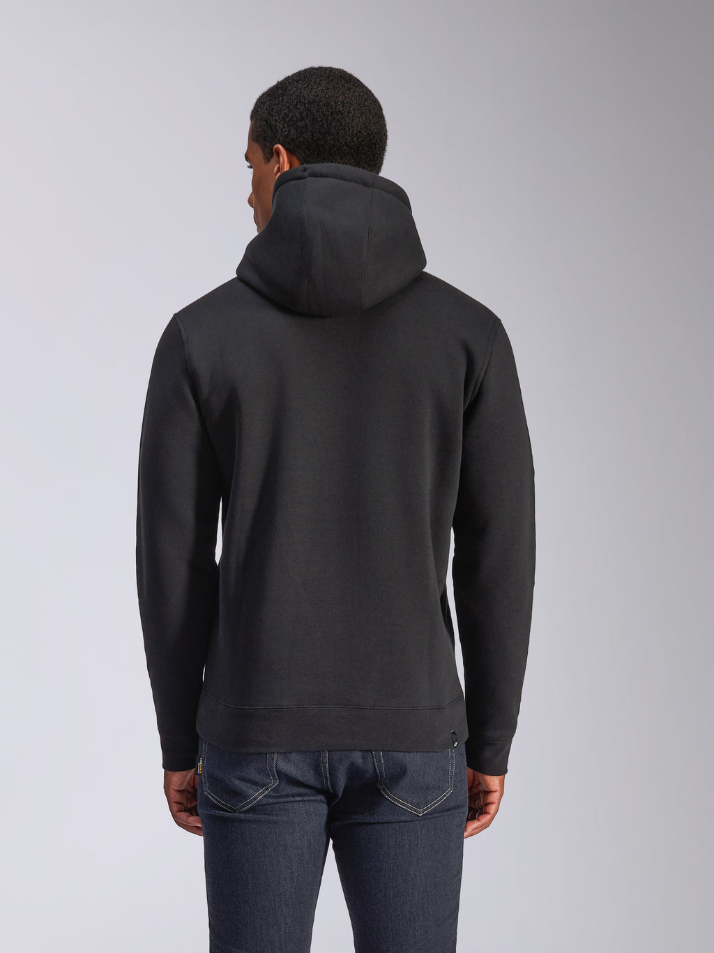 Alpinestars Blaze V3 Hoodie, vista posteriore di una felpa in pile nera a pullover, casual streetwear, con polsini e orlo a coste, cappuccio foderato in jersey, indossata con jeans blu scuro