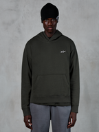 Alpinestars Essentials Ageless Hoodie, streetwear casual, pullover Off Black con un piccolo logo Alpinestars bianco sul petto, indossata con un berretto nero, design minimalista con tasca a marsupio frontale e finitura stone-wash