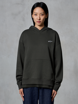 Felpa con cappuccio Alpinestars Essentials Ageless, Off Black, indossata da una modella, con un piccolo logo Astars bianco sul petto, tasca a marsupio frontale, finitura stone-wash, streetwear casual in pile pregiato