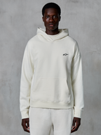 Alpinestars Essentials Ageless Hoodie, bianco sporco, indossata da un modello uomo, piccolo logo nero sul petto, tasca a marsupio frontale, maniche lunghe, streetwear casual ispirato al motorsport