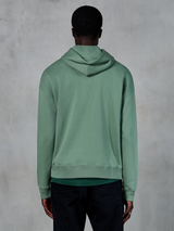 Felpa con cappuccio Alpinestars Essentials Ageless, abbigliamento sportivo casual, verde Cactus, vista posteriore su modello, finitura stone wash, abbinata a pantaloni neri, design lifestyle minimalista