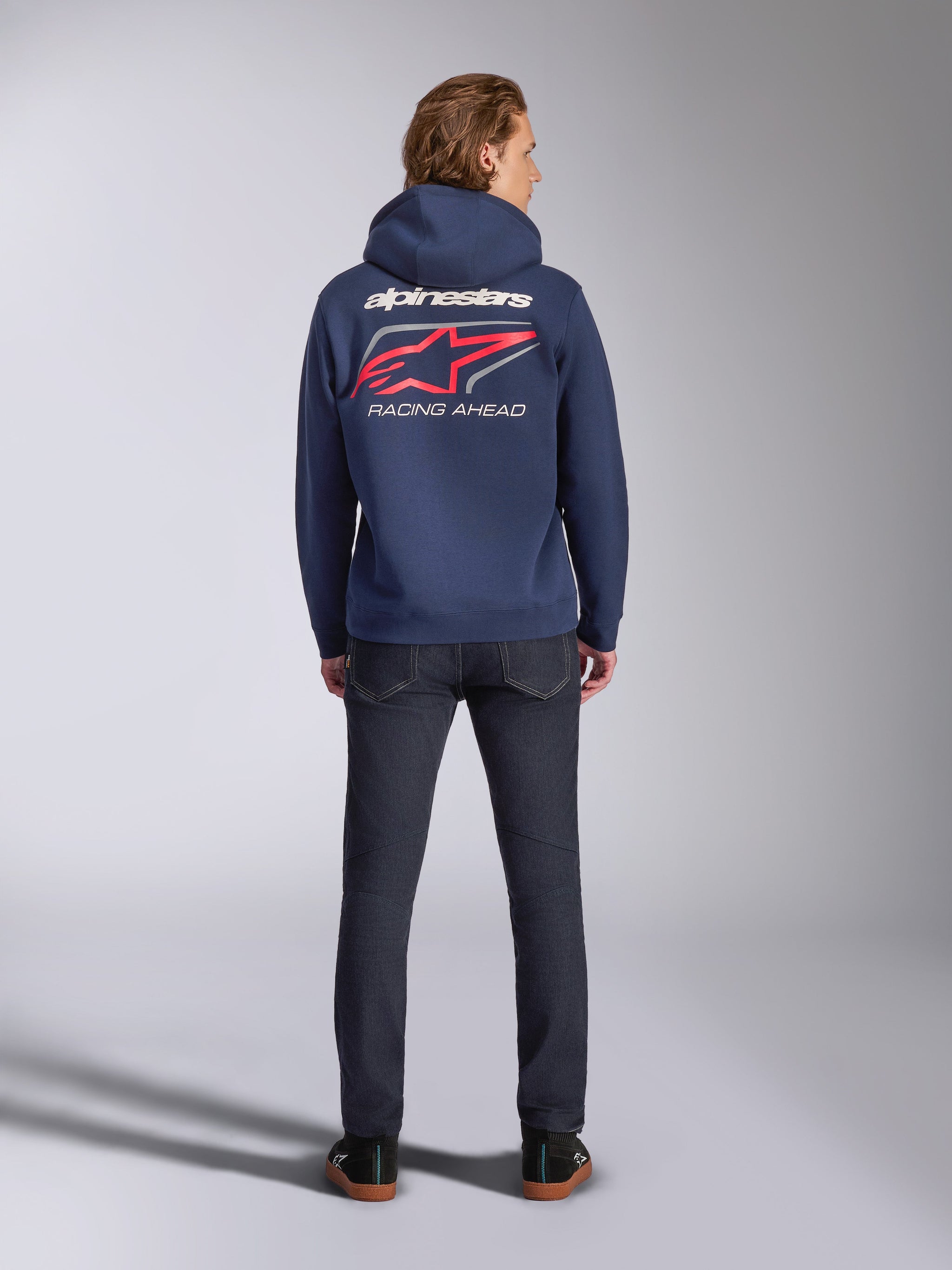 Felpa con cappuccio Alpinestars Formulation in blu navy, vista posteriore, con grande scritta Alpinestars bianca e logo rosso con stampa 'RACING AHEAD', streetwear casual ispirato al motorsport abbinato a jeans scuri