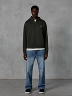 Alpinestars Essentials Ageless Zip Hoodie, felpa con cappuccio e zip integrale, Off Black, con un piccolo logo Alpinestars bianco sul petto, indossata da un modello con t-shirt bianca e jeans blu, vestibilità rilassata, streetwear casual ispirato al motorsport