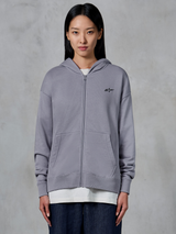Felpa con cappuccio Alpinestars Essentials Ageless Zip, Silver, streetwear casual, felpa in pile con zip integrale e piccolo logo Alpinestars nero sul petto, tasca a marsupio divisa, indossata dalla modella sopra una t-shirt bianca e jeans scuri