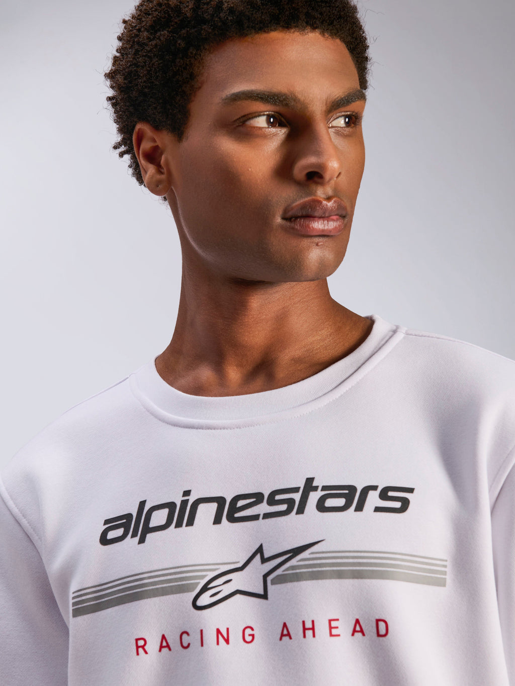 Alpinestars Bettern Crew, felpa girocollo in pile bianco, logo Alpinestars nero con linee orizzontali grigie e scritta 'Racing Ahead' rossa, streetwear casual ispirato al motorsport