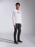 Alpinestars Bettern Crew, felpa girocollo bianca, con logo Alpinestars nero e scritta rossa 'Racing Ahead', streetwear casual motorsport, indossata da un modello con pantaloni scuri e sneakers nere