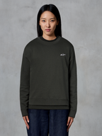 Alpinestars Essentials Ageless Crew, felpa girocollo premium, Off Black, con un piccolo logo Alpinestars bianco sul petto, stile streetwear casual, indossata da una modella con jeans scuri