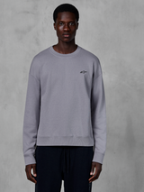 Alpinestars Essentials Ageless Crew, felpa girocollo color argento indossata da un modello, con un piccolo logo a stella nero sul petto, vestibilità rilassata con polsini e orlo a costine, abbigliamento streetwear casual motorsport