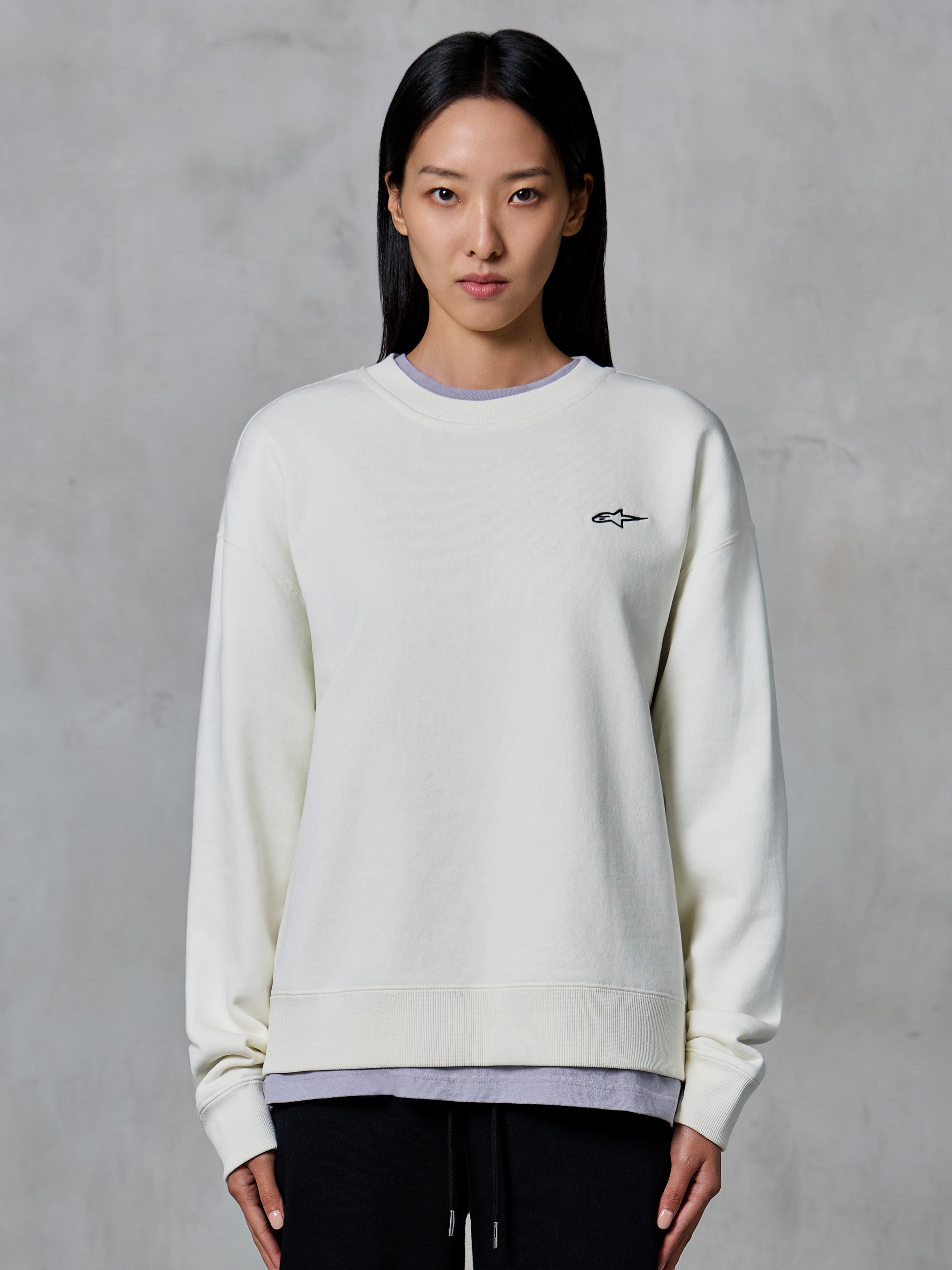 Alpinestars Essentials Ageless Crew, felpa girocollo, Off White, con un piccolo logo Alpinestars nero sul petto, abbigliamento lifestyle casual indossato da una donna