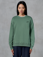 Alpinestars Essentials Ageless Crew, felpa girocollo, verde cactus, indossata da una modella, piccolo logo nero sul petto, colletto, polsini e fondo a costine, streetwear casual motorsport