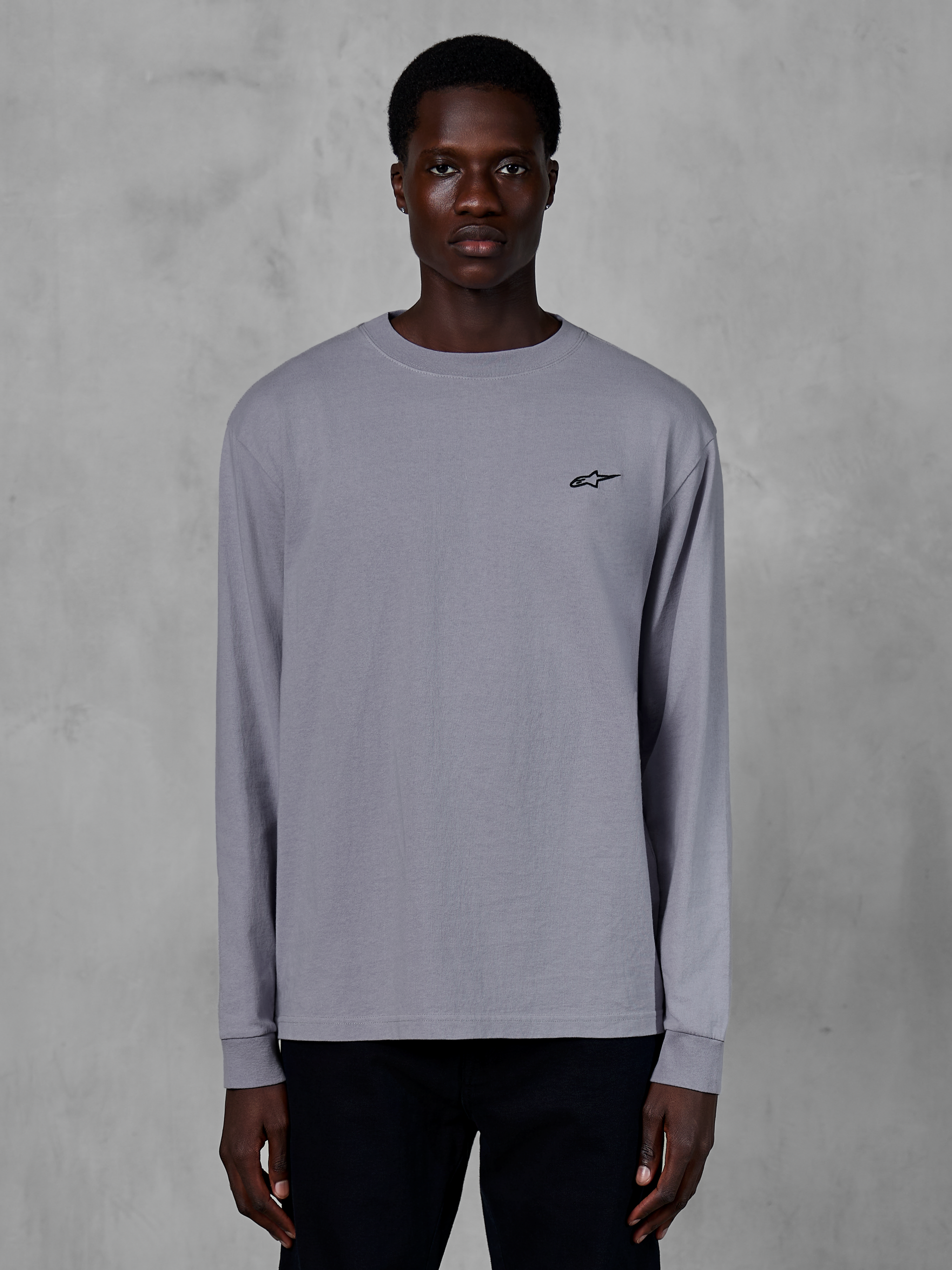 Alpinestars Essentials Ageless LS Tee, maglia a maniche lunghe, colore argento, indossata da un modello, con piccolo logo Alpinestars nero sul petto, vestibilità contemporanea rilassata, streetwear casual in cotone biologico