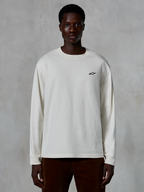 Alpinestars Essentials Ageless LS Tee, t-shirt a maniche lunghe, bianco sporco, piccolo logo a stella nero sul petto, streetwear casual, vestibilità rilassata, indossata da un modello