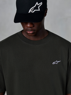 Alpinestars Essentials Ageless SS Tee, t-shirt a maniche corte, nero, con un piccolo logo Alpinestars bianco sul petto, indossata con un cappellino da baseball nero con logo, stile casual motorsport streetwear