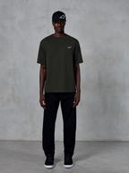 Alpinestars Essentials Ageless SS Tee, maglietta a maniche corte, nero, con un piccolo logo Alpinestars bianco sul petto, indossata da un modello con cappellino e pantaloni neri per un look lifestyle pulito