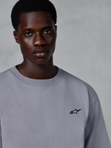 Alpinestars Essentials Ageless SS Tee, maglietta a maniche corte, argento, con un piccolo logo a stella nero sul petto, indossata da un modello, abbigliamento casual lifestyle streetwear