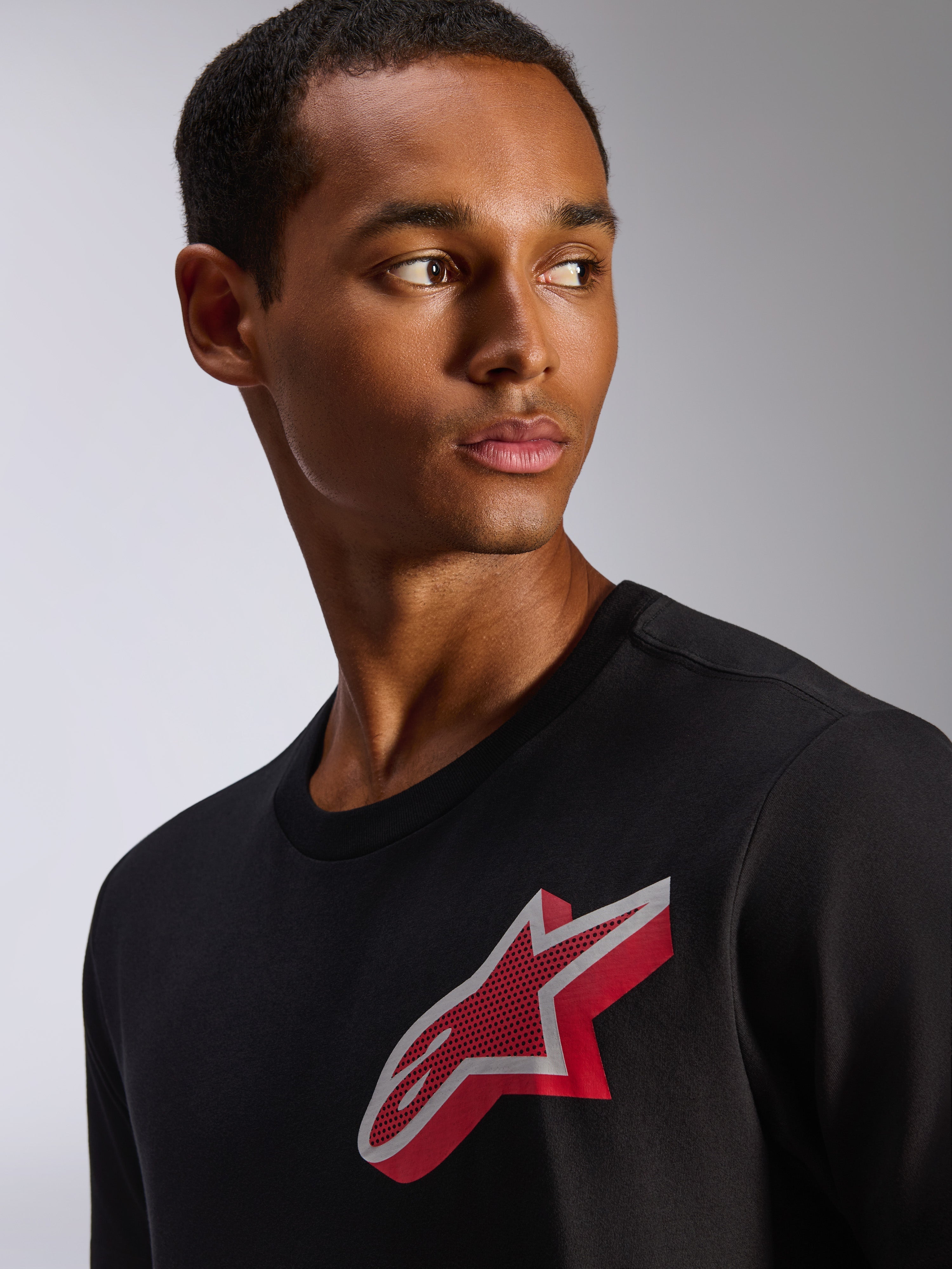 Alpinestars Shaded CSF Tee, t-shirt a maniche corte, nero, con logo Astars in lamina a gradiente rosso e bianco sul petto, abbigliamento casual d'ispirazione motorsport indossato da un modello