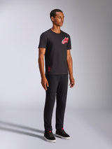Alpinestars Shaded CSF Tee, maglietta a maniche corte, nero, logo Astars con stampa a gradiente in lamina inclinata rosso e bianco, streetwear casual motorsport, inquadratura a figura intera di un modello che indossa pantaloni neri e sneaker