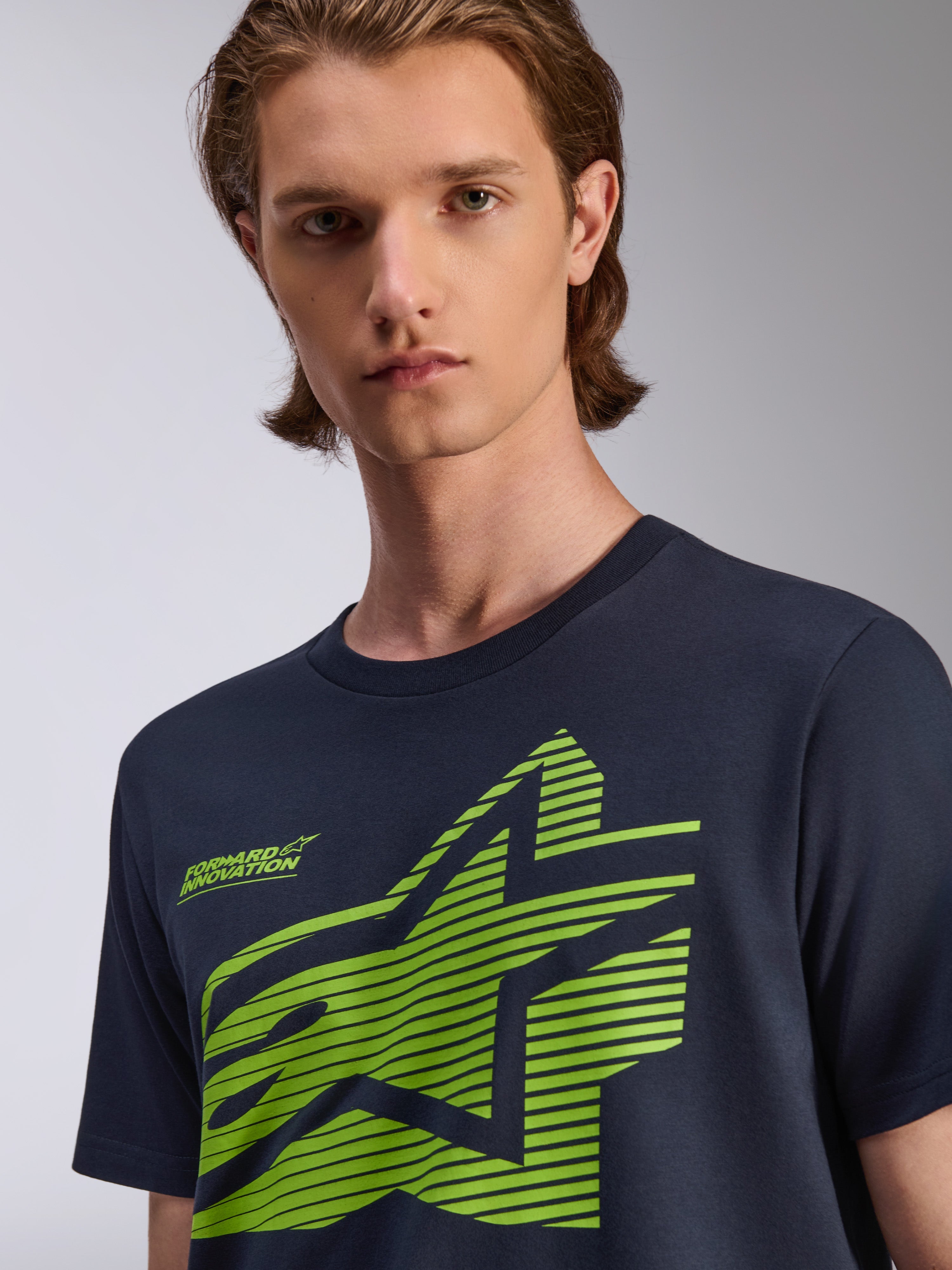 T-shirt Alpinestars Fasting CSF, maglietta a maniche corte, blu navy, grafica a stella geometrica verde lime con scritta Forward Innovation, indossata da un modello, abbigliamento streetwear casual motorsport